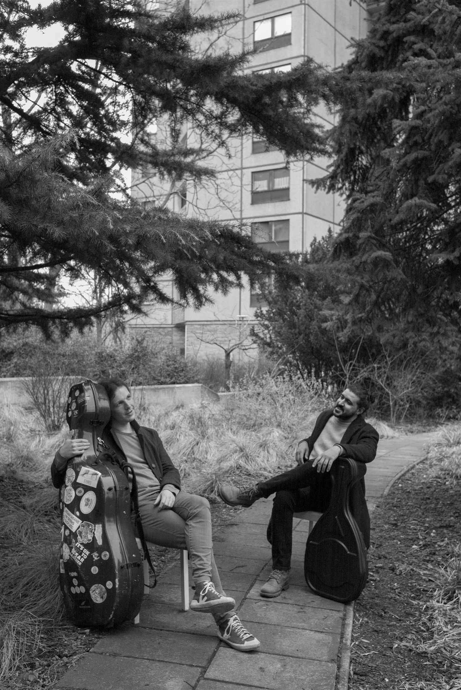 Sufian and Plush Rebel seated outdoors with instrument cases